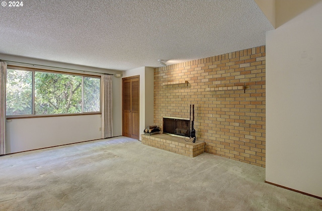 unfurnished living room featuring a textured ceiling, a fireplace, light colored carpet, and brick wall