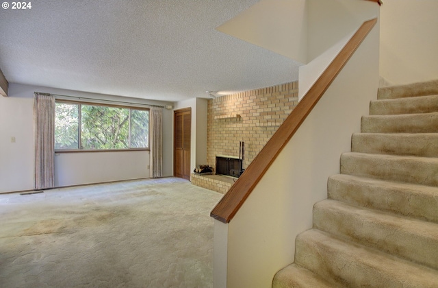 interior space featuring carpet, a textured ceiling, and a brick fireplace