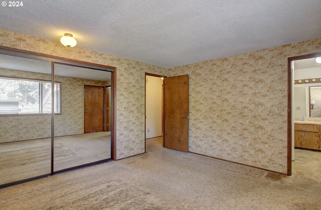 unfurnished bedroom with connected bathroom, a closet, a textured ceiling, and sink