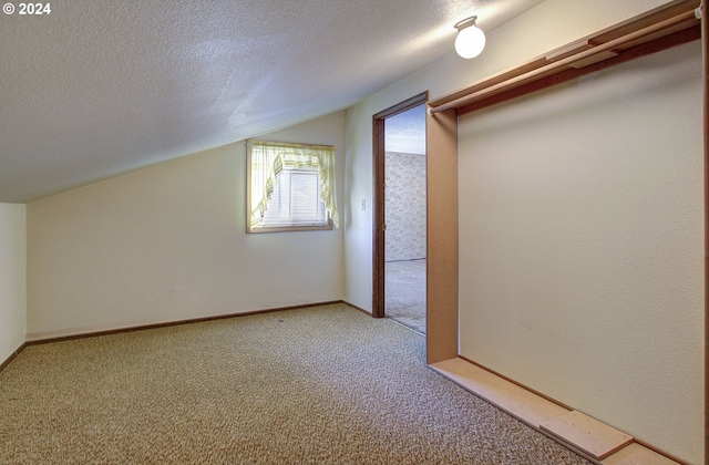 additional living space with a textured ceiling, light colored carpet, and lofted ceiling