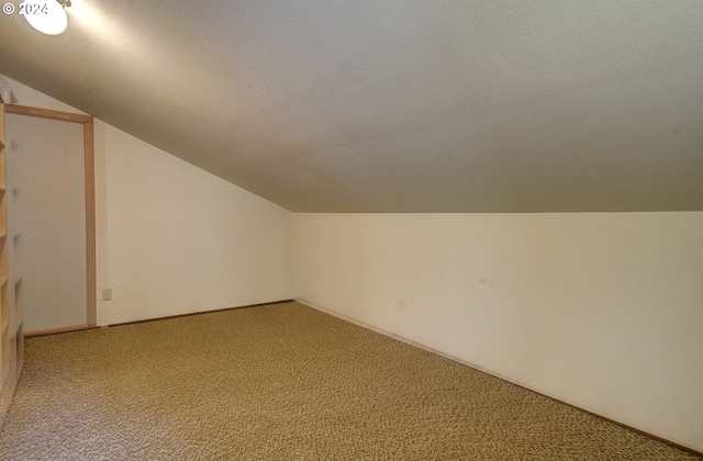 bonus room featuring a textured ceiling, carpet floors, and lofted ceiling