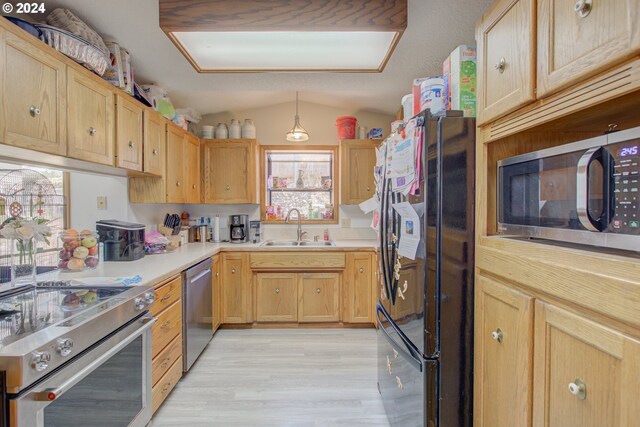 kitchen with sink, stainless steel appliances, pendant lighting, lofted ceiling, and light hardwood / wood-style floors