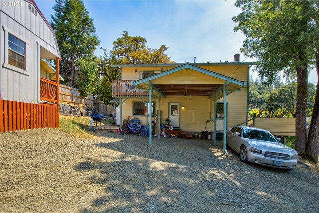 back of house featuring a balcony and a carport