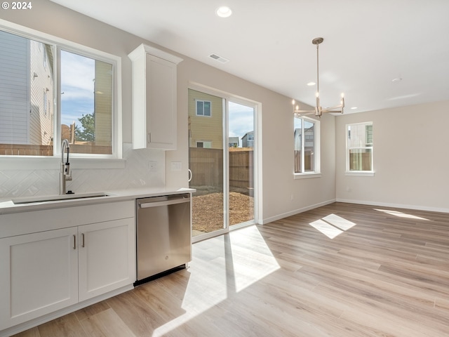 interior space featuring stainless steel dishwasher, backsplash, white cabinets, and sink