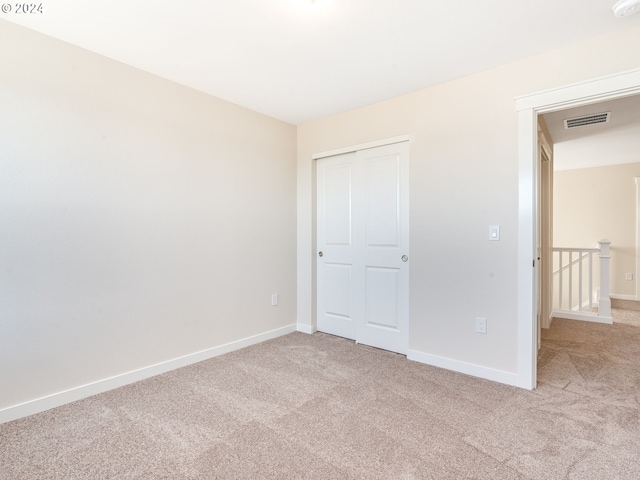 unfurnished bedroom featuring light carpet and a closet