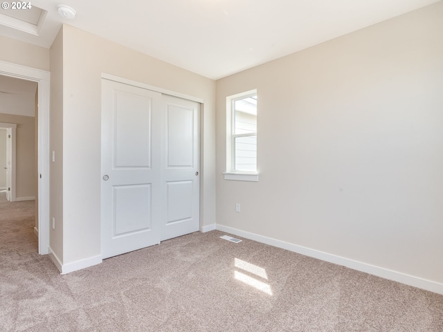 unfurnished bedroom featuring light colored carpet and a closet