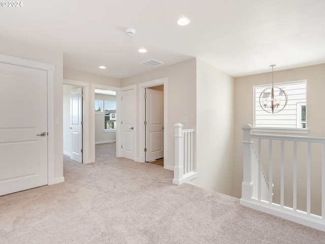 carpeted spare room with a chandelier