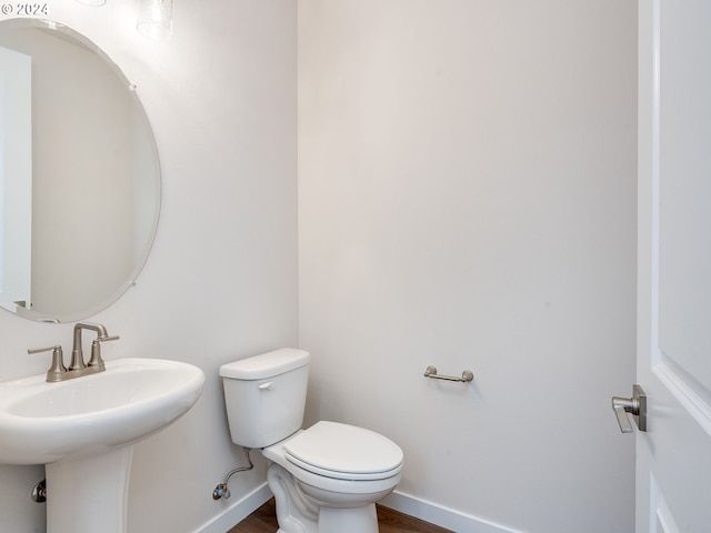 bathroom featuring wood-type flooring, toilet, and sink