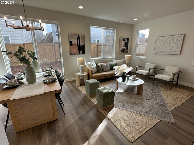 living room with a notable chandelier, dark hardwood / wood-style floors, and a healthy amount of sunlight