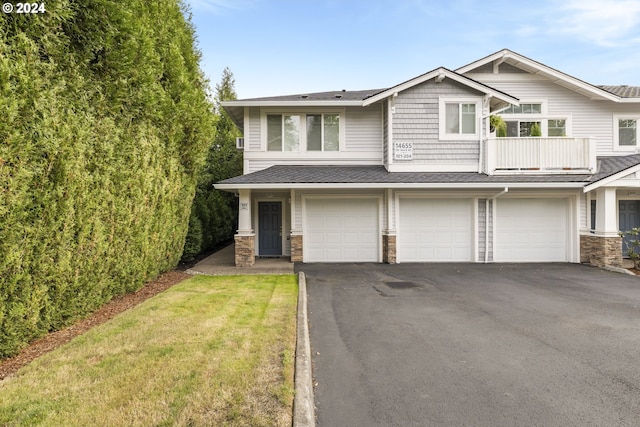 view of front of home featuring a balcony, a garage, and a front yard