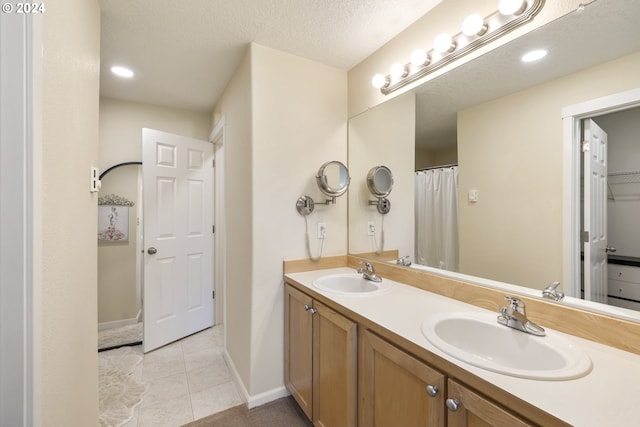 bathroom with tile patterned floors, vanity, and a textured ceiling