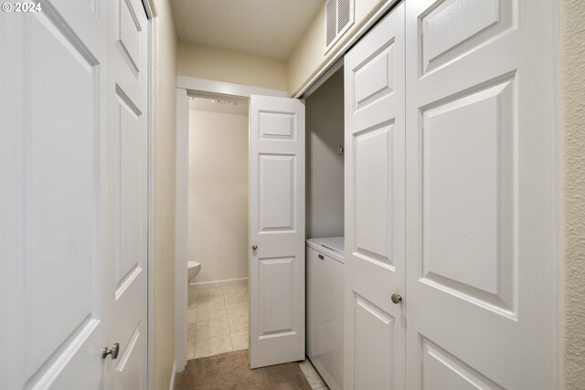 hallway featuring washer / clothes dryer and light tile patterned flooring