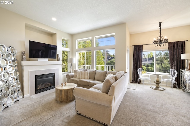 carpeted living room featuring a tiled fireplace, plenty of natural light, and a textured ceiling