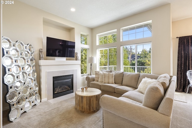 carpeted living room with a textured ceiling, a tiled fireplace, and a high ceiling