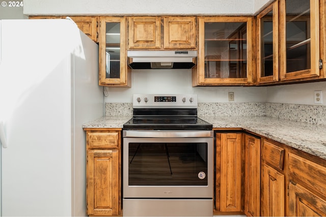 kitchen with white refrigerator, light stone countertops, and stainless steel electric range