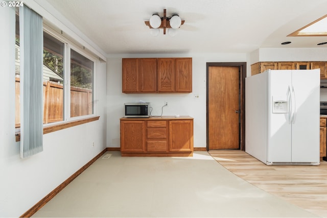 kitchen with white refrigerator with ice dispenser and light hardwood / wood-style flooring