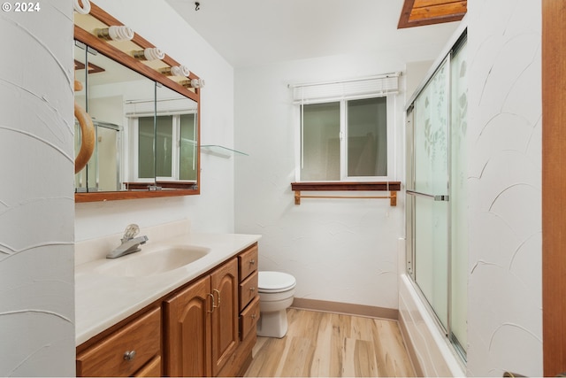 full bathroom with enclosed tub / shower combo, vanity, hardwood / wood-style floors, and toilet