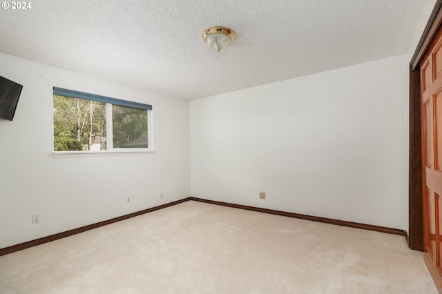 unfurnished bedroom featuring a textured ceiling and light colored carpet