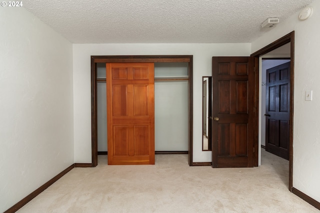 unfurnished bedroom with a textured ceiling, light colored carpet, and a closet