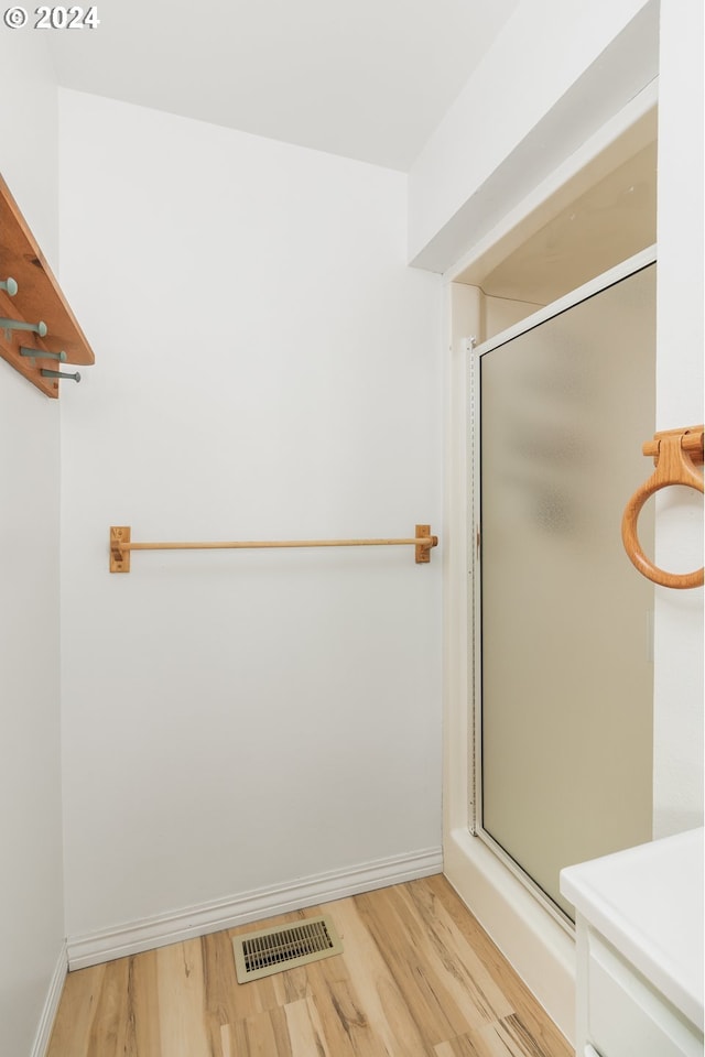 bathroom with hardwood / wood-style flooring and a shower with shower door