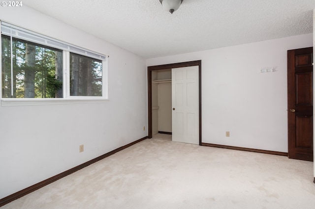 unfurnished bedroom with light carpet, a textured ceiling, and a closet