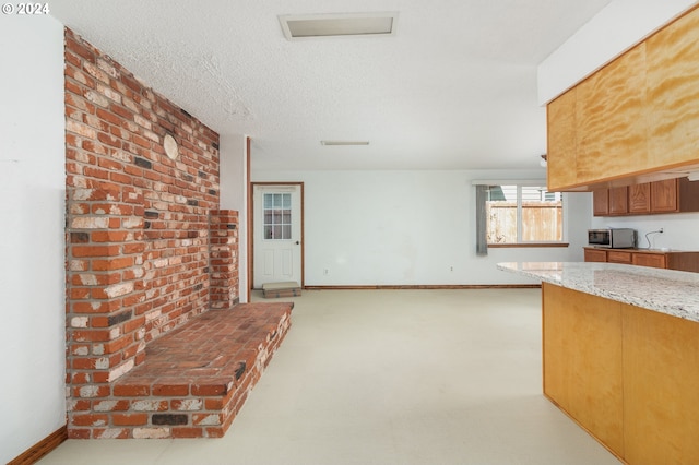 kitchen featuring a textured ceiling, light carpet, and light stone counters