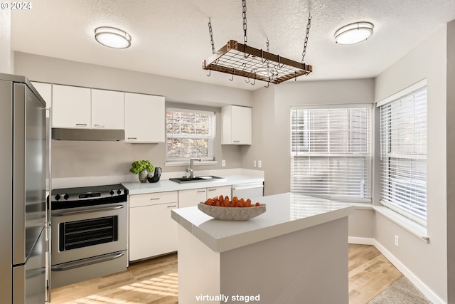 kitchen featuring white cabinetry, sink, stainless steel appliances, light hardwood / wood-style floors, and a textured ceiling