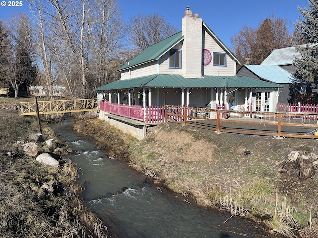 view of side of property featuring metal roof, a chimney, and fence