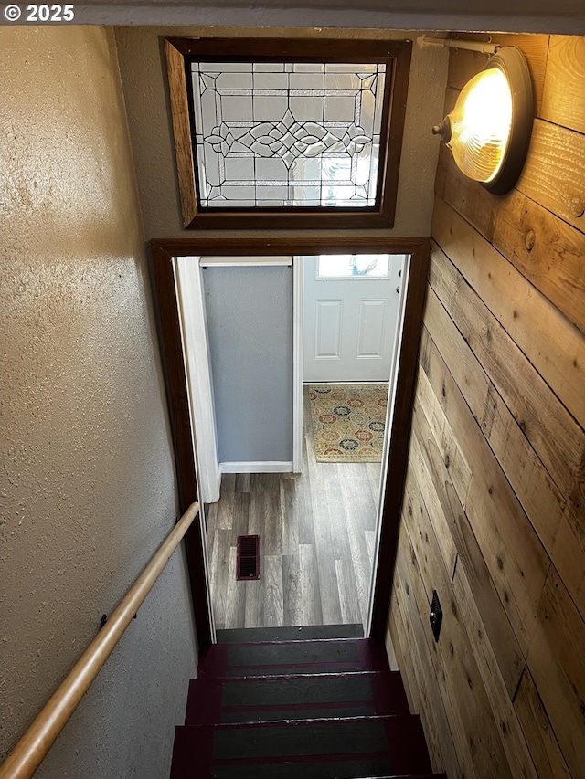 doorway to outside with a textured wall, stairway, and wood finished floors