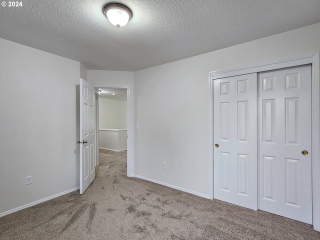 unfurnished bedroom featuring carpet, a textured ceiling, and a closet