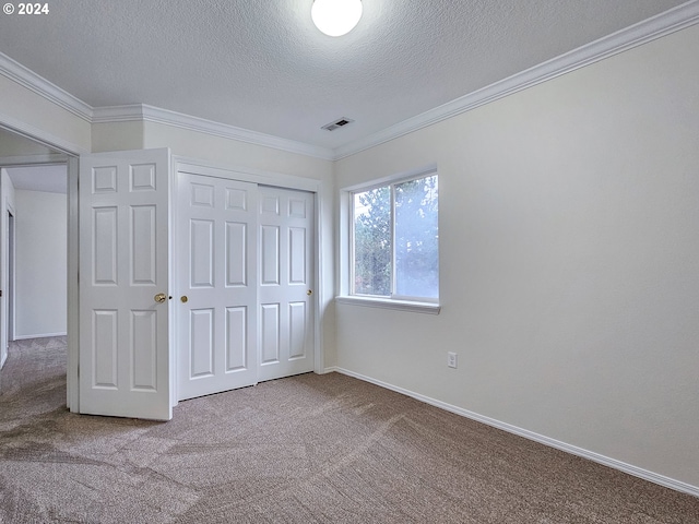 unfurnished bedroom with a closet, carpet, a textured ceiling, and ornamental molding