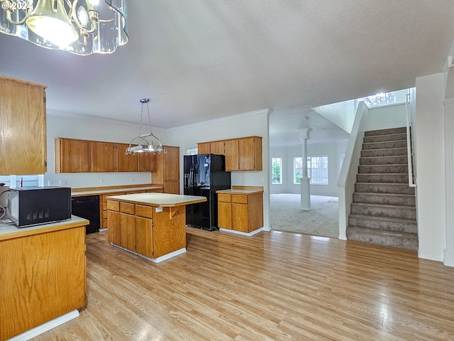 kitchen featuring black appliances, pendant lighting, light hardwood / wood-style flooring, an inviting chandelier, and a kitchen island