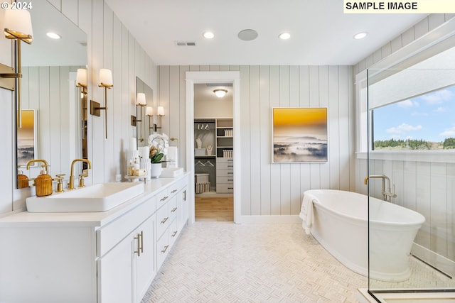 bathroom featuring visible vents, a walk in closet, a freestanding bath, vanity, and recessed lighting