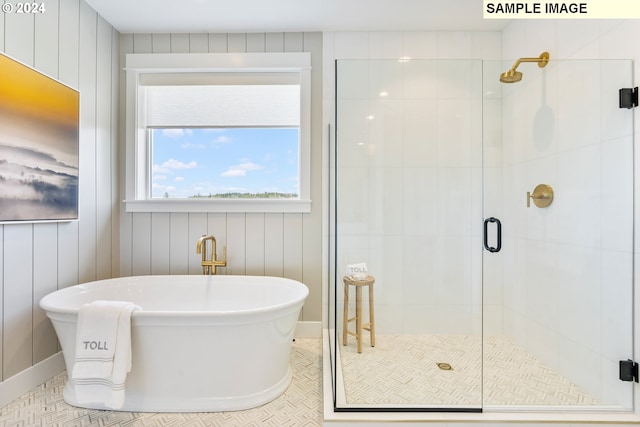 bathroom with a stall shower, a freestanding tub, baseboards, and tile patterned floors