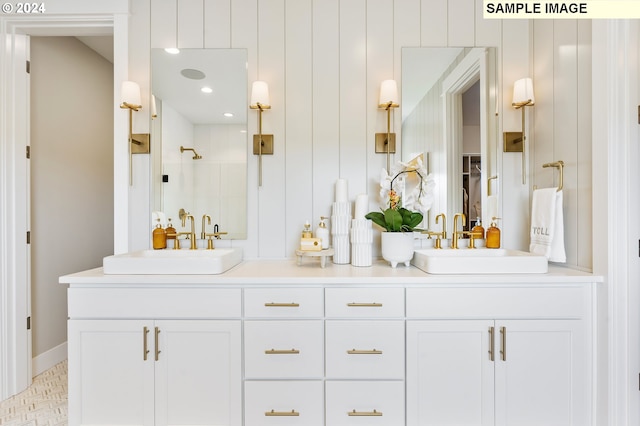 full bath featuring a tile shower, double vanity, and a sink