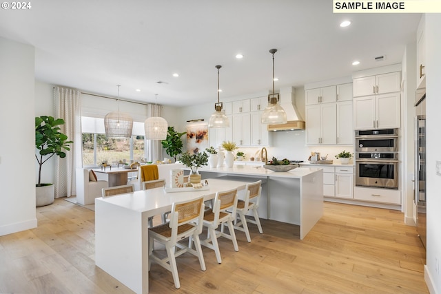 kitchen with a breakfast bar, custom exhaust hood, white cabinetry, appliances with stainless steel finishes, and a large island