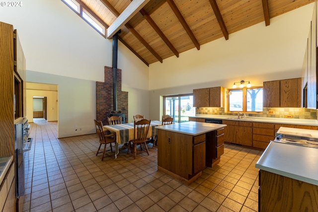 kitchen featuring decorative backsplash, sink, high vaulted ceiling, a kitchen island, and light tile patterned flooring