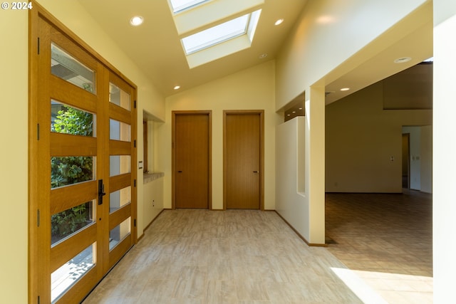 hallway with light hardwood / wood-style flooring, high vaulted ceiling, and a skylight