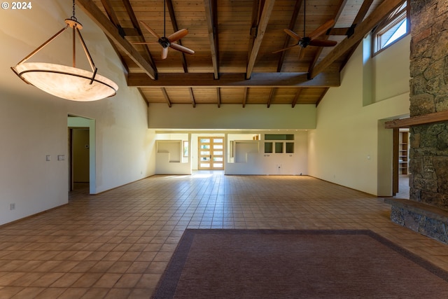 unfurnished living room with beam ceiling, ceiling fan, a stone fireplace, high vaulted ceiling, and wood ceiling