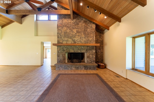 unfurnished living room with high vaulted ceiling, a stone fireplace, ceiling fan, beamed ceiling, and light tile patterned flooring