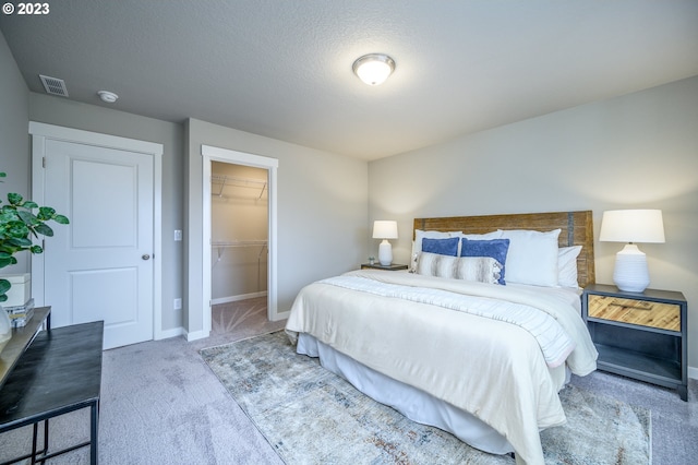 bedroom with a walk in closet, carpet floors, a closet, and a textured ceiling