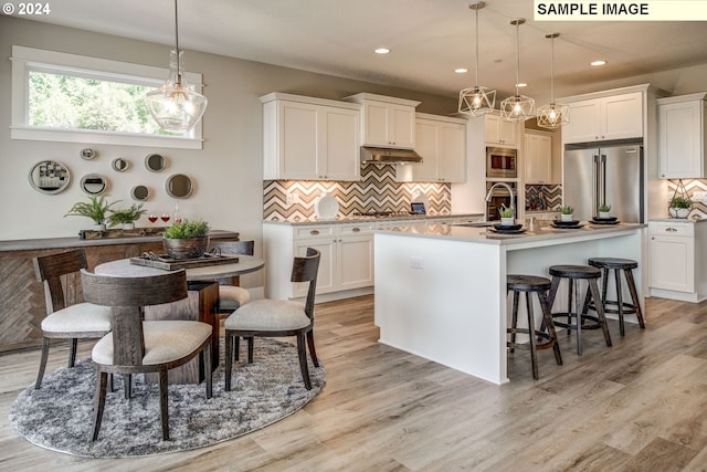 kitchen with an island with sink, stainless steel appliances, white cabinets, and an inviting chandelier