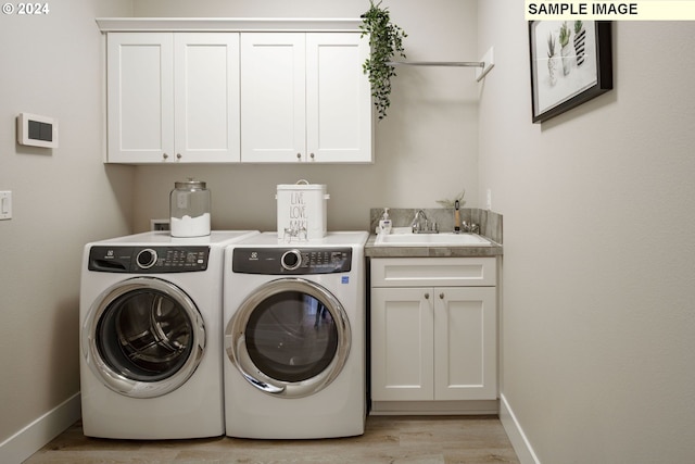 clothes washing area featuring cabinets, light wood-type flooring, washer and dryer, and sink