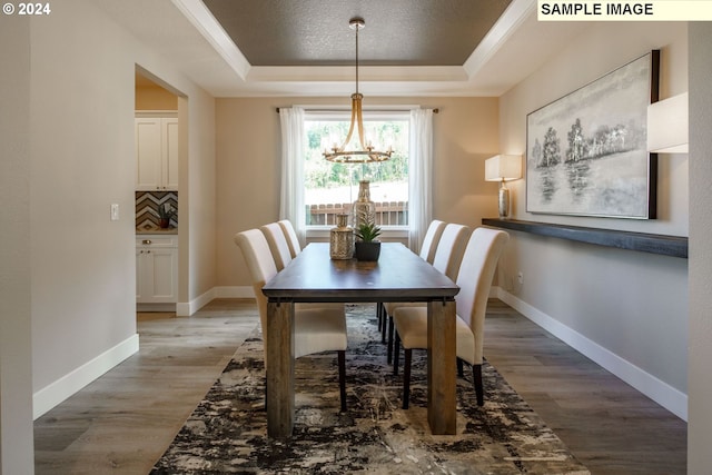 dining space featuring hardwood / wood-style flooring, a tray ceiling, and a chandelier