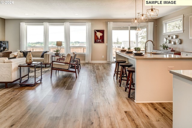 kitchen with pendant lighting, a chandelier, a textured ceiling, a kitchen breakfast bar, and light hardwood / wood-style flooring