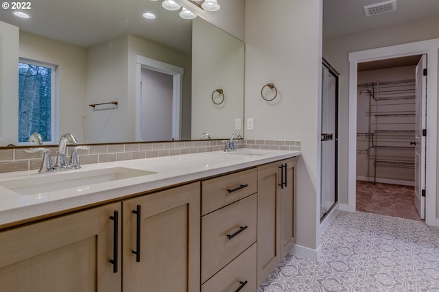 bathroom with vanity, backsplash, and a shower with door