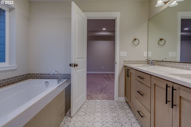 bathroom featuring tile patterned flooring, vanity, and tiled tub