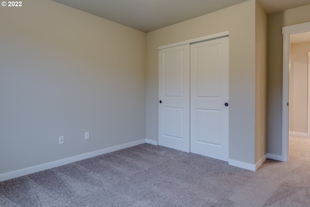 unfurnished bedroom with light carpet and a closet