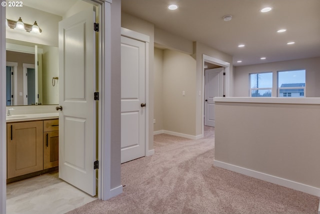 hallway with light carpet and sink