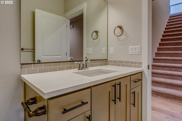 bathroom with wood-type flooring, vanity, and tasteful backsplash